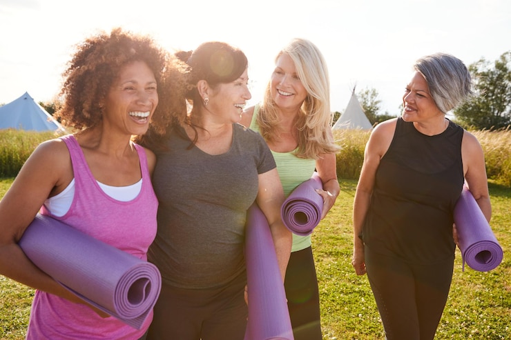 group-mature-female-friends-outdoor-yoga-retreat-walking-along-path-through-campsite_1218270-5832