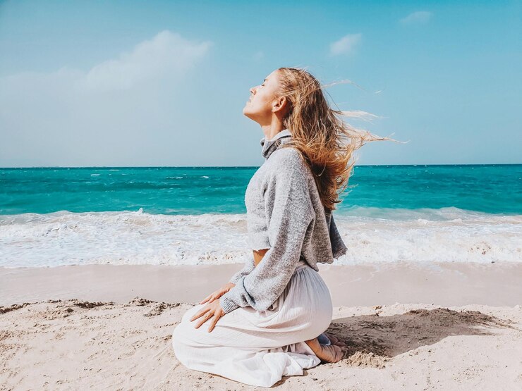side-view-woman-meditating-beach-against-sky_1048944-28442666