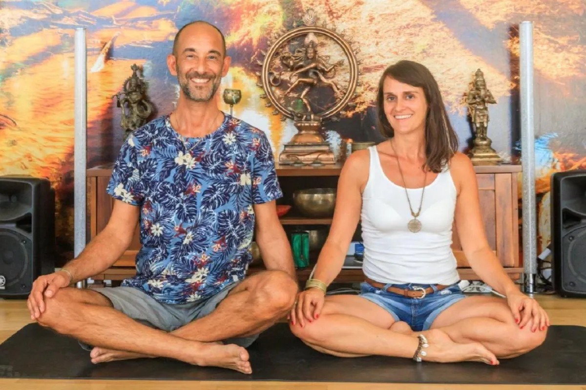 a group of people sitting on mats with hands together