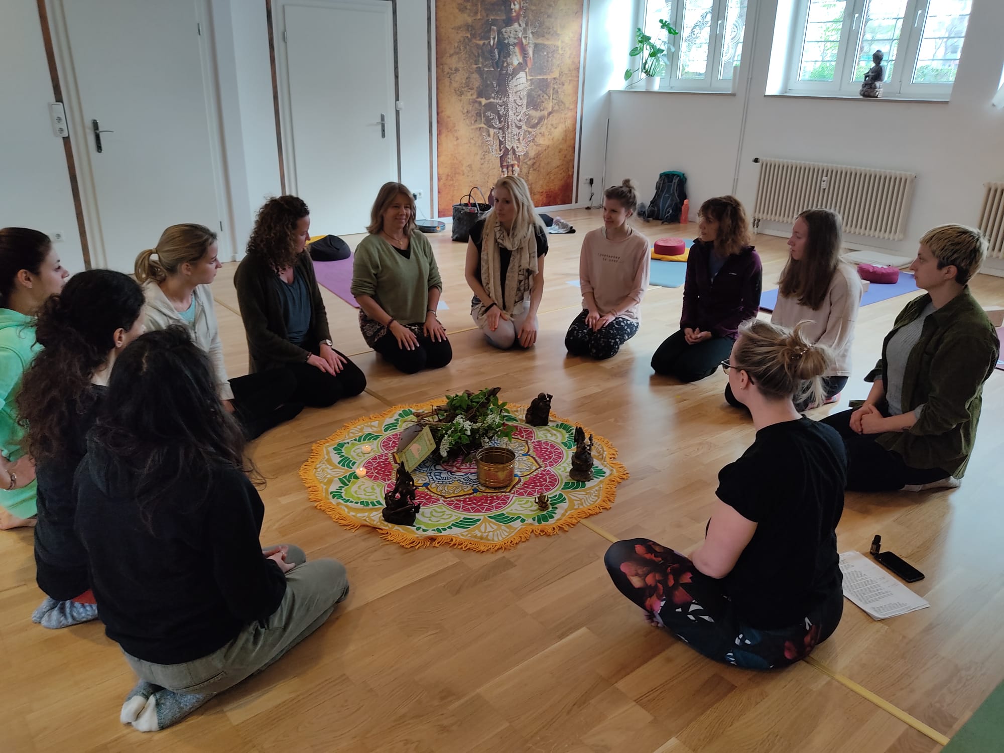 a group of people sitting on mats with hands together